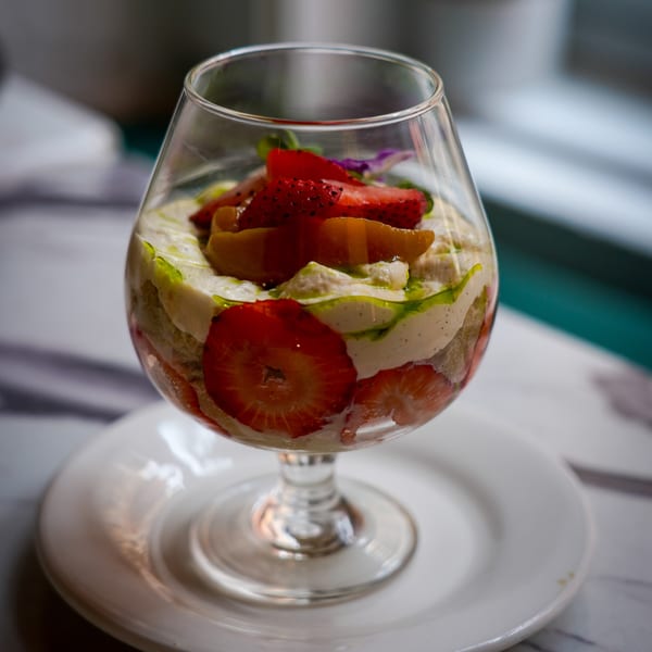 Vegan strawberry and cream parfait with fruit and green drizzle in a stemmed glass.