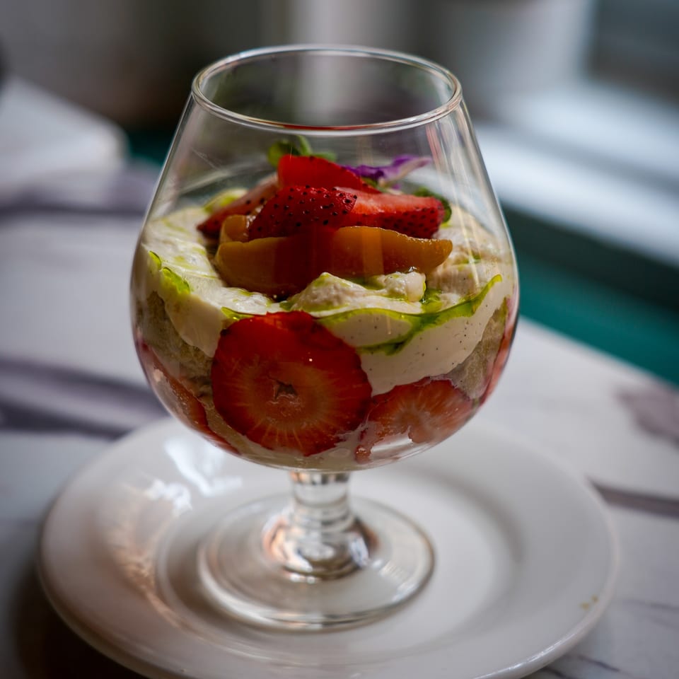 Vegan strawberry and cream parfait with fruit and green drizzle in a stemmed glass.